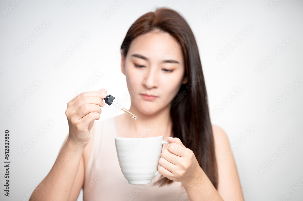 Woman dripping cbd oil inside tea cup, cofee cup - Alternative medicine, vitamins and supplements concept - Focus on dropper Woman dripping cbd oil inside tea cup, cofee cup - Alternative medicine, vitamins and supplements concept - Focus on dropper