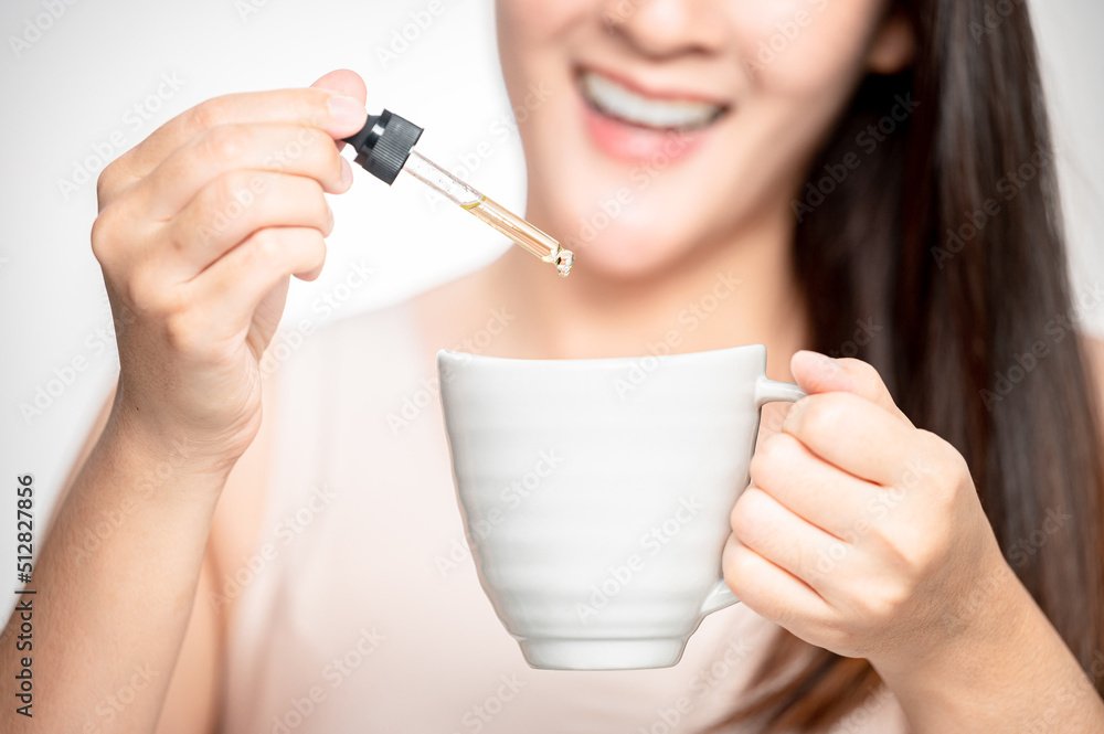 Woman dripping cbd oil inside tea cup, cofee cup - Alternative medicine, vitamins and supplements concept - Focus on dropper Woman dripping cbd oil inside tea cup, cofee cup - Alternative medicine, vitamins and supplements concept - Focus on dropper
