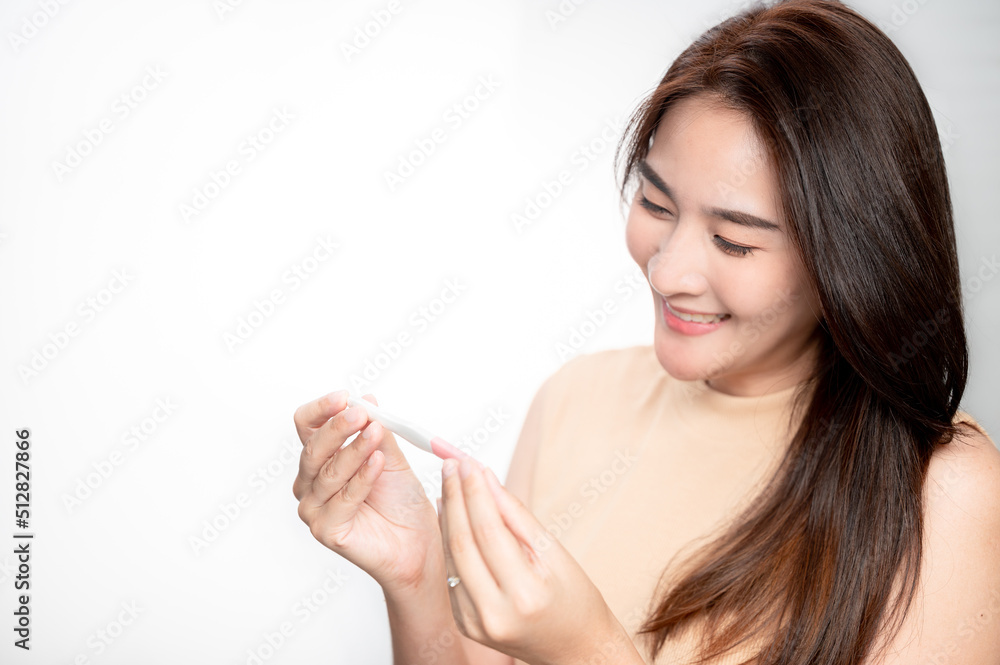 Asian woman holding pregnancy test feeling happy by positive result. female health problems and infertility. successful treatment IUI Intra – Uterine Insemination and ICSI Asian woman holding pregnancy test feeling happy by positive result. female health problems and infertility. successful treatment IUI Intra – Uterine Insemination and ICSI