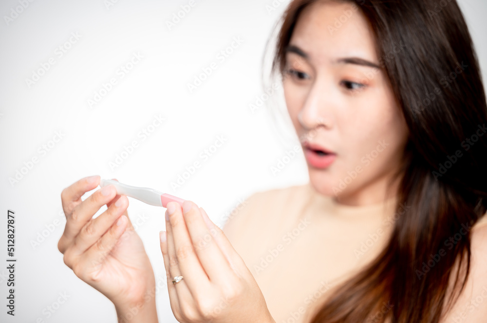Asian woman holding pregnancy test feeling happy by positive result. female health problems and infertility. successful treatment IUI Intra – Uterine Insemination and ICSI Asian woman holding pregnancy test feeling happy by positive result. female health problems and infertility. successful treatment IUI Intra – Uterine Insemination and ICSI