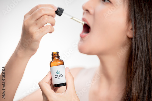 Asian woman dripping cbd oil into her mouth. Close up asian women taking CBD Oil for sleep. Medical cannabis. Vitamins and supplements new choice for health.