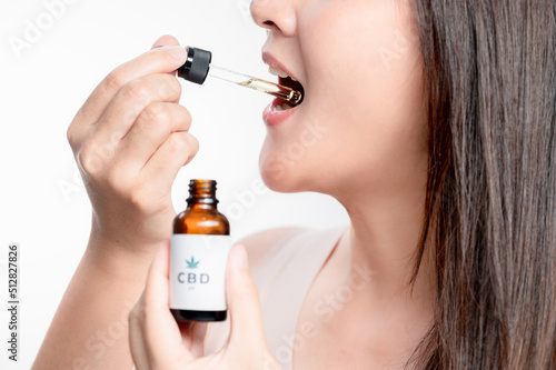 Asian woman dripping cbd oil into her mouth. Close up asian women taking CBD Oil for sleep. Medical cannabis. Vitamins and supplements new choice for health.