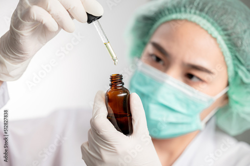 close up Medical technologist asian woman looks at a bottle of CBD oil. Research on cannabis extracts. Sleep supplement. Medical marijuana. vitamins and supplements healthy alternatives.. photo