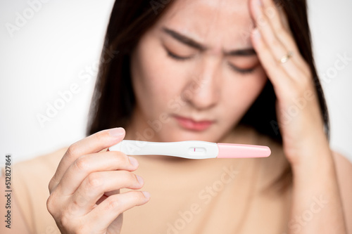 Asian woman holding pregnancy test feeling disappointed by negative result female health problems and infertility. or unwilling pregnancy, abortion.