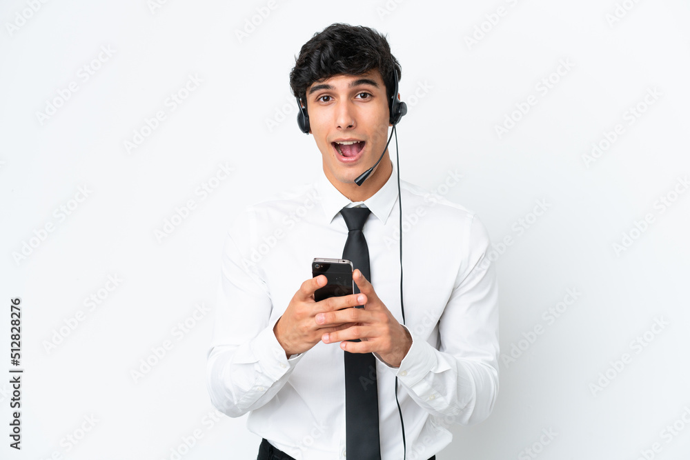 Telemarketer man working with a headset isolated on white background surprised and sending a message Telemarketer man working with a headset isolated on white background surprised and sending a message