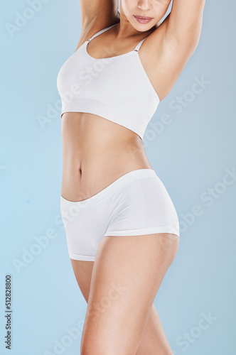 Close up of woman posing in white underwear and against a blue studio background. Fit, sporty model standing alone, isolated and showing her perfect body. Take care of your body and health © Azeemud-Deen Jacobs/peopleimages.com