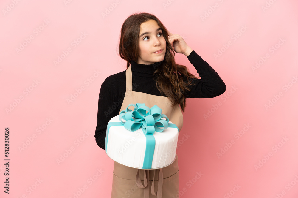 Little Pastry chef holding a big cake isolated on pink background having doubts and thinking Little Pastry chef holding a big cake isolated on pink background having doubts and thinking