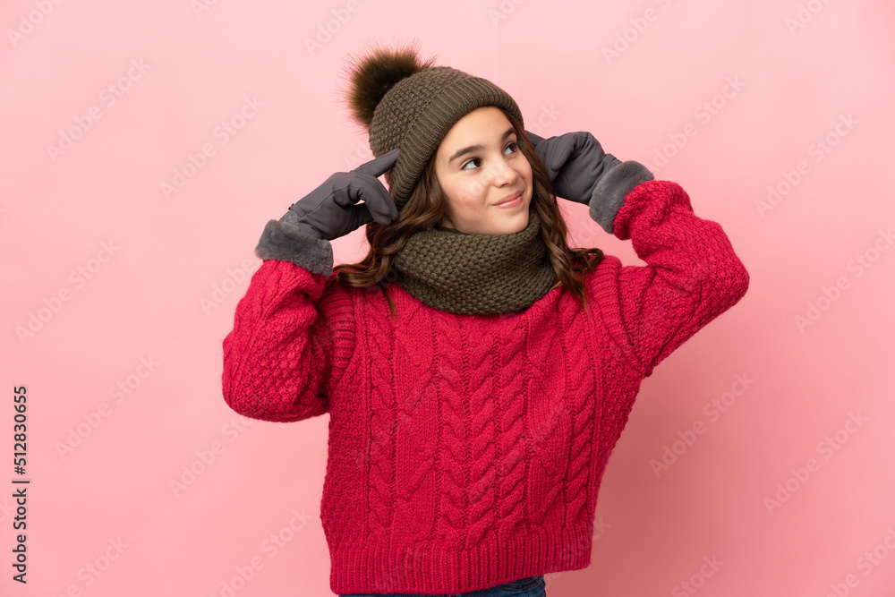 Little girl with winter hat isolated on pink background having doubts and thinking Little girl with winter hat isolated on pink background having doubts and thinking