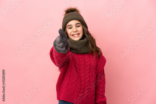 Little girl with winter hat isolated on pink background shaking hands for closing a good deal © luismolinero