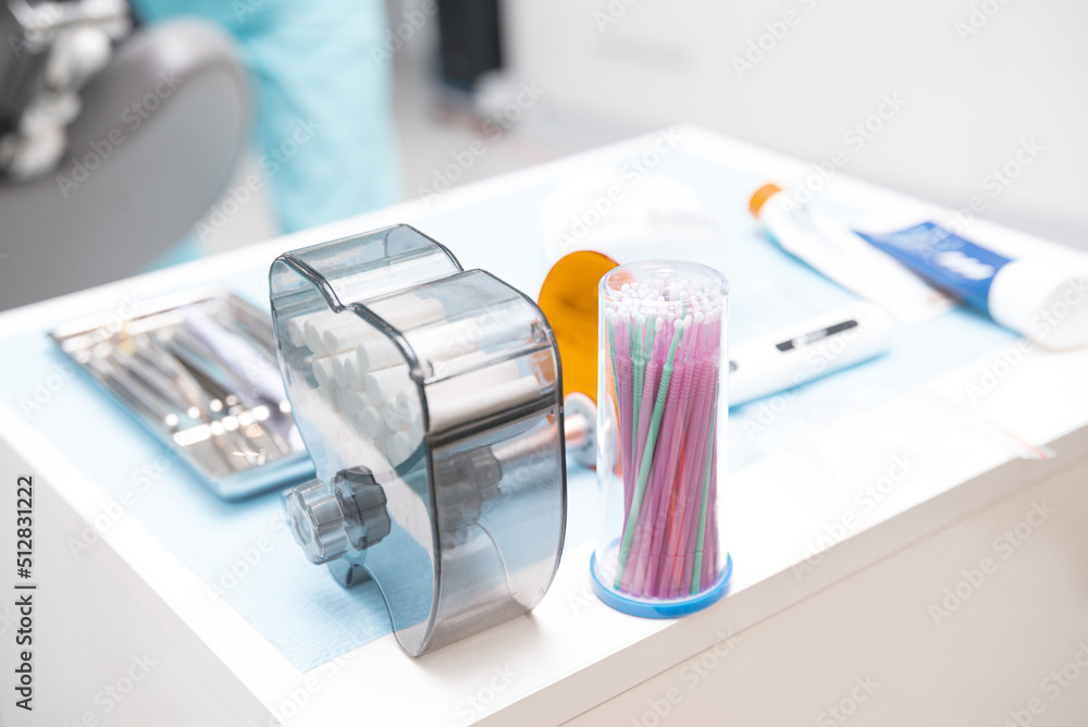 Close up photo of dentistry tools and cotton rolls on a tray in a cabinet.
