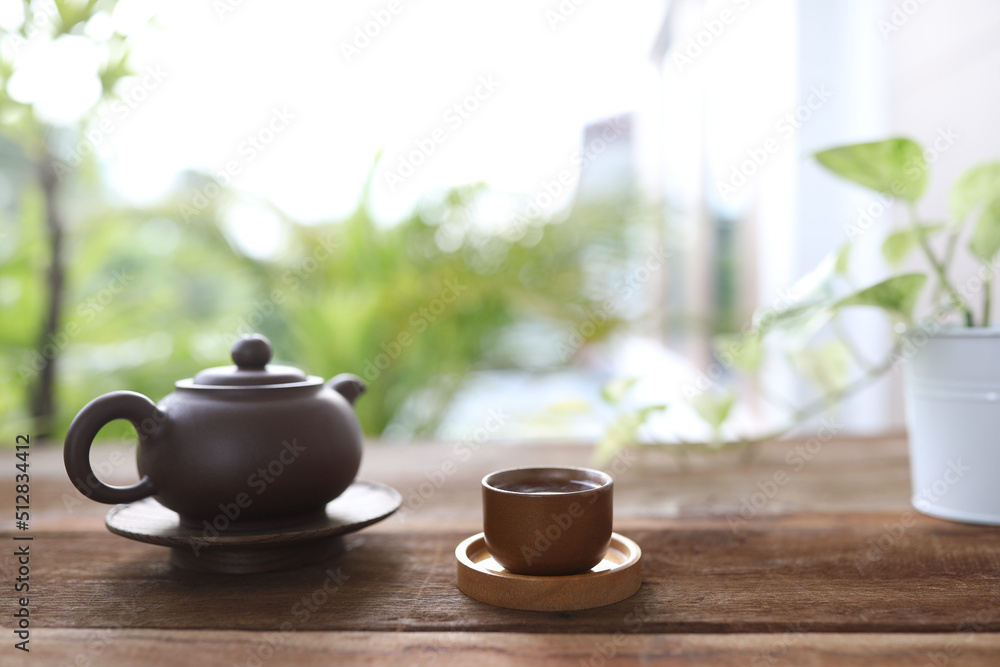Brown earthenware teapot and tea cup and books Brown earthenware teapot and tea cup and books