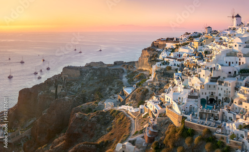 Santorini at Sundown. The famous town of Oia in the sunset. A line of sailing yachts at sea. Romantic holidays. Oia, Santorini, Greece