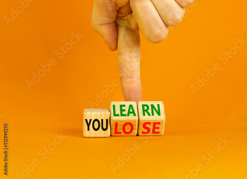 We learn or lose symbol. Concept words We learn and We lose on wooden cubes. Businessman hand. Beautiful orange table orange background. Business and we learn or lose concept. Copy space.