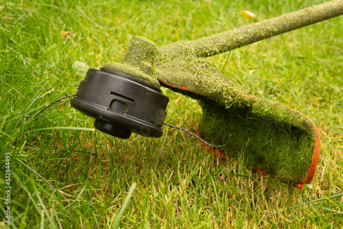 Petrol trimmer mows green grass. Photography with movement photo