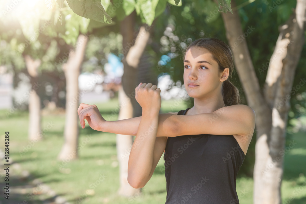 Teenage girl doing muscle stretching exercise in a city park. Teenage girl doing muscle stretching exercise in a city park.