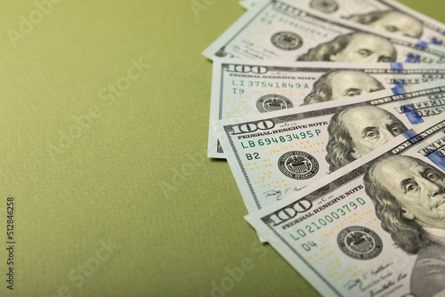 Money, stacks of US hundred dollar bills on an olive background. Money is scattered on the table. Concepts of finance and economy. Money accumulation concept. Saving currency. Investments. Copy space.