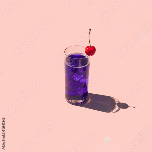 Colorful cocktail with cherry on pastel light pink background. Creative drink concept. Minimalistic beverage composition.