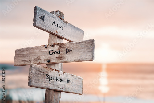 and god spoke text quote on wooden crossroad signpost outdoors on beach with pink pastel sunset colors. Romantic theme. photo