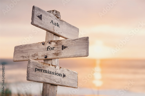 ask for permission text quote on wooden crossroad signpost outdoors on beach with pink pastel sunset colors. Romantic theme.