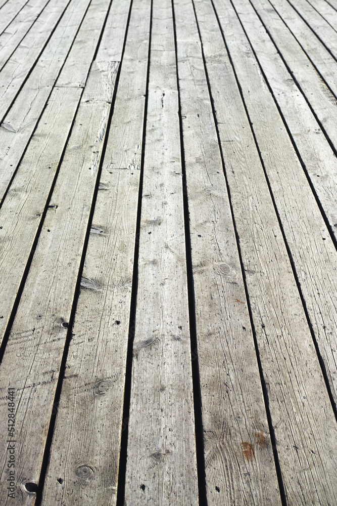 Closeup of a wooden plank surface. Light grey vintage flooring with slats forming an outdoor terrace. Old textures of hard wood floor used as a walkway or deck. Long vertical outdoor floorboards Closeup of a wooden plank surface. Light grey vintage flooring with slats forming an outdoor terrace. Old textures of hard wood floor used as a walkway or deck. Long vertical outdoor floorboards