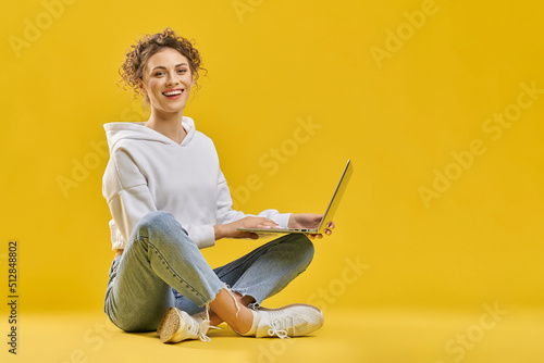 Photography Smiling female student in casual clothes, surfing internet on laptop inside