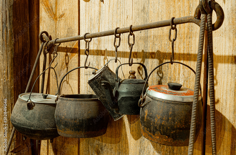 Antique iron pots hanging on an iron stand in the farm's kitchen