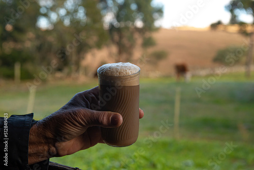 man milking the cow and mixing with a cup of coffee the so-called 