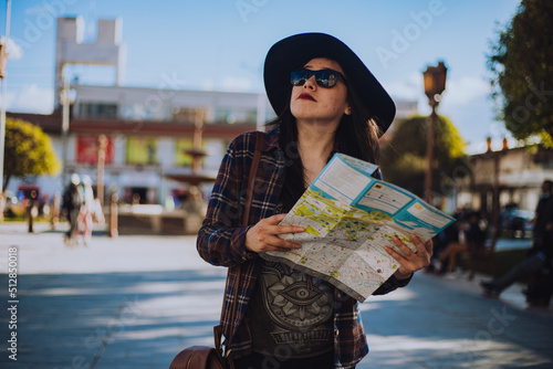 Mujer caminando por una plaza de Sudamérica con un plano en la mano. Concepto de viajes y turismo. photo