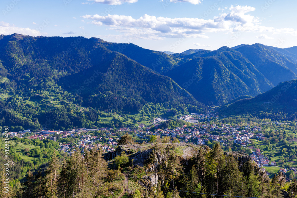 View from rock to town of Smolyan with meadows for cattle walking and houses between mountain range of Rhodope Mountains