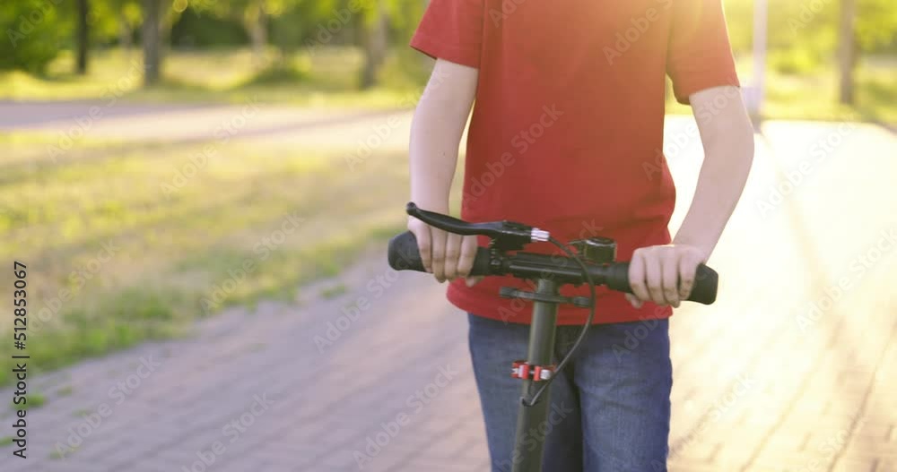 Child with kick scooter. Young boy riding on scooter on path in the park in summer. Kids leisure activity, sport Child with kick scooter. Young boy riding on scooter on path in the park in summer. Kids leisure activity, sport