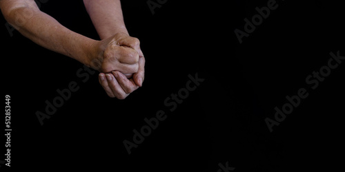 Hands of an elderly woman in wrinkles on a black background close-up