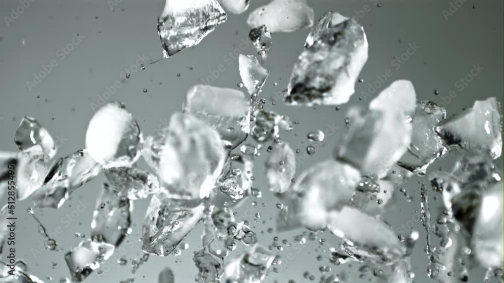 Pieces of ice with splashes of water soar up and fall. On a gray background. Filmed on a high-speed camera at 1000 fps. Pieces of ice with splashes of water soar up and fall. On a gray background. Filmed on a high-speed camera at 1000 fps.