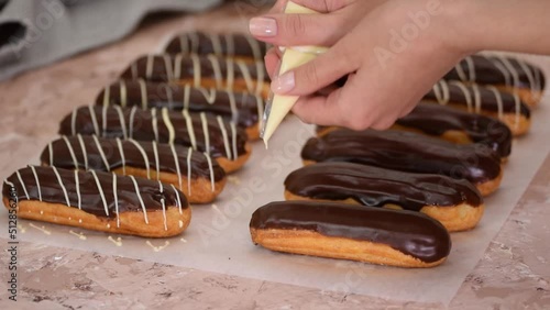Pastry chef pours white chocolate on French eclairs.