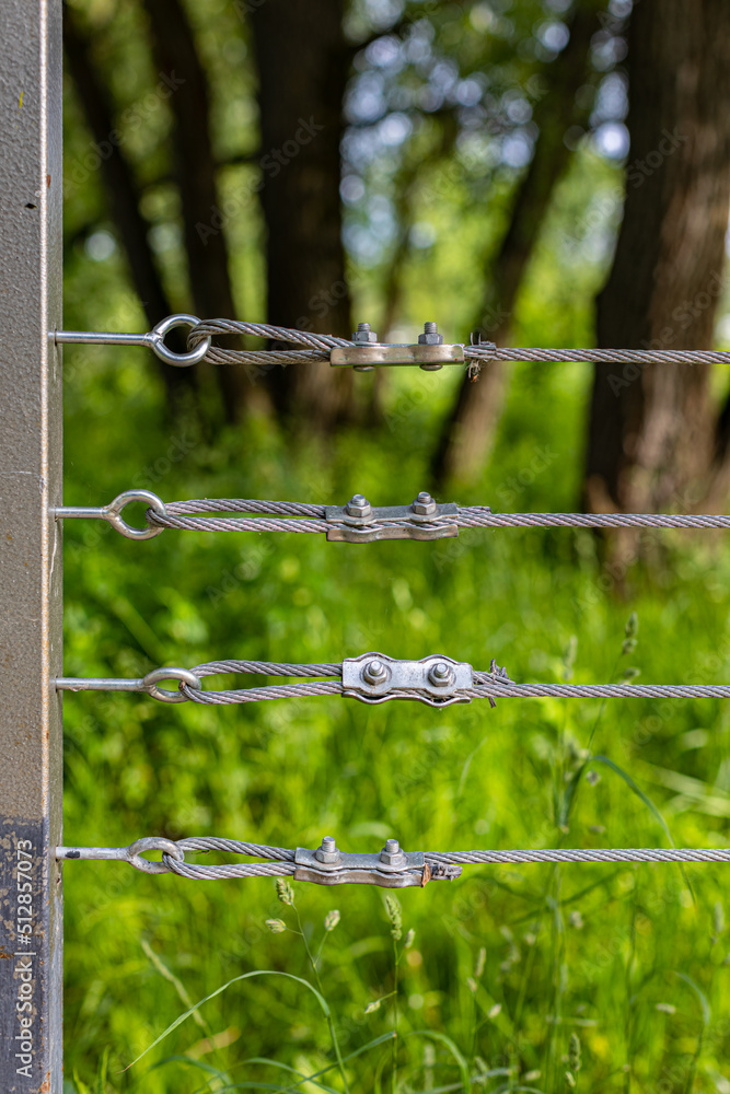 fixing a steel cable on a fence in a park fixing a steel cable on a fence in a park