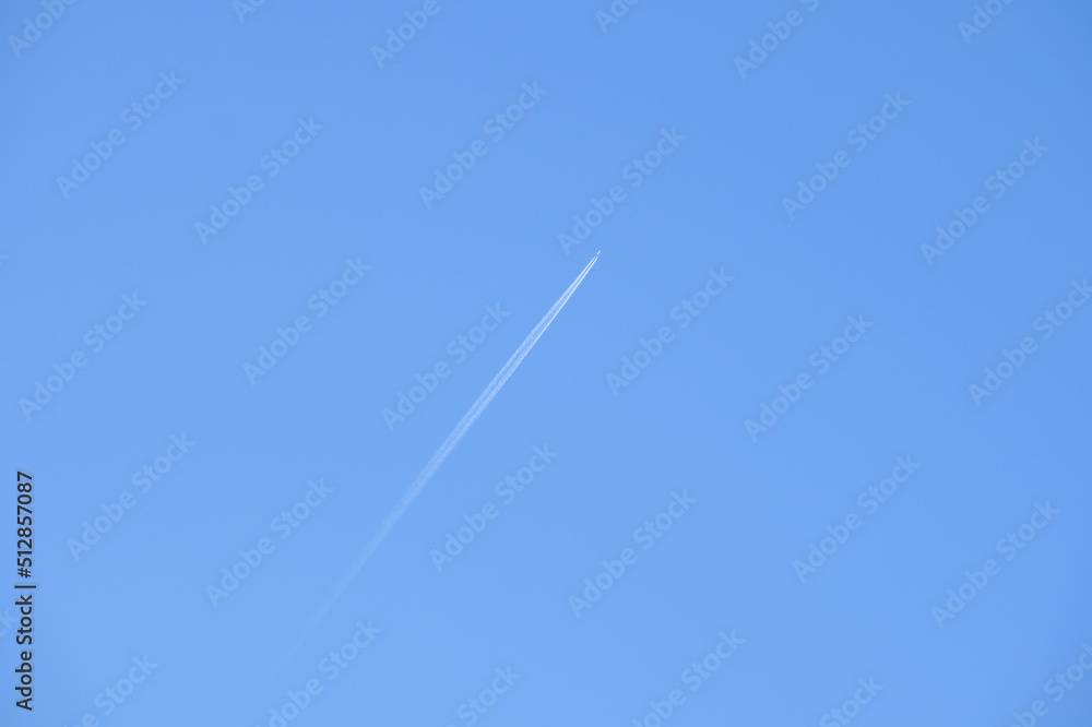 Distant passenger jet plane flying on high altitude on clear blue sky leaving white smoke trace of contrail behind. Air transportation concept Distant passenger jet plane flying on high altitude on clear blue sky leaving white smoke trace of contrail behind. Air transportation concept