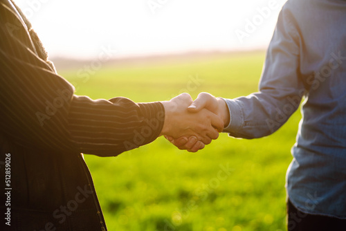 Two farmers making agreement with handshake in green wheat field. Agricultural business.