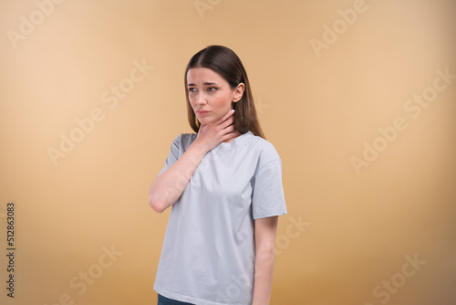 Young lady suffering from sore throat on a beige background photo