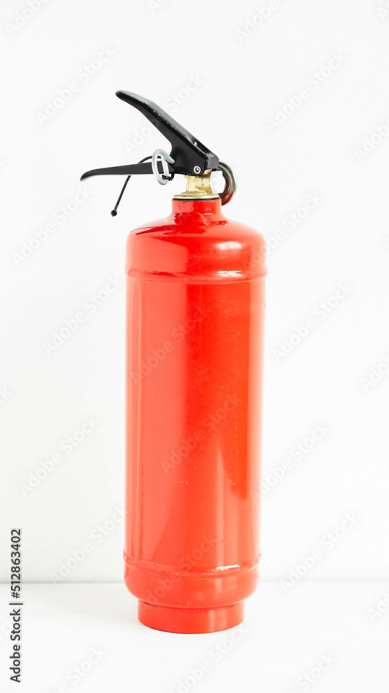 Red fire extinguisher on a white wall background Red fire extinguisher on a white wall background