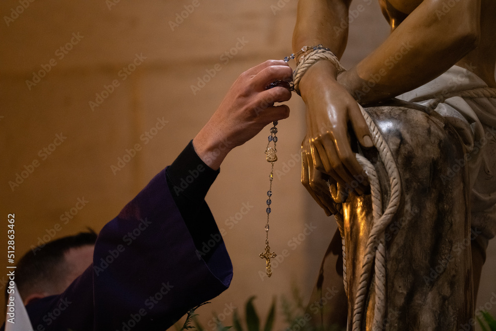catholic priest putting the rosary to the figure of jesus christ