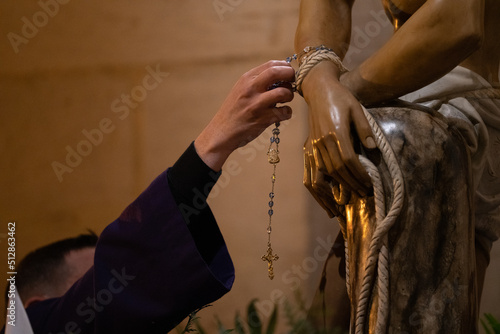 catholic priest putting the rosary to the figure of jesus christ