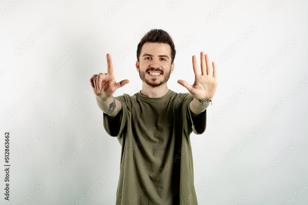 Cheerful caucasian man wearing casual clothes posing isolated over white background showing and pointing up with fingers number seven while smiling. Cheerful caucasian man wearing casual clothes posing isolated over white background showing and pointing up with fingers number seven while smiling.