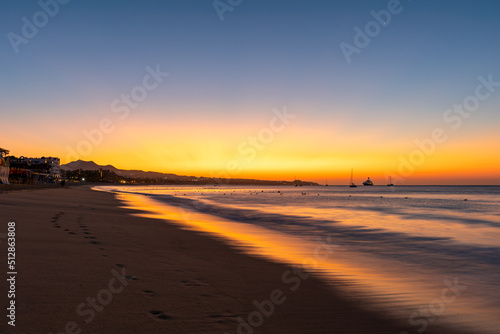 A vibrant sunrise with light reflecting in waves on the coastline of M  dano beach in Cabo San Lucas 