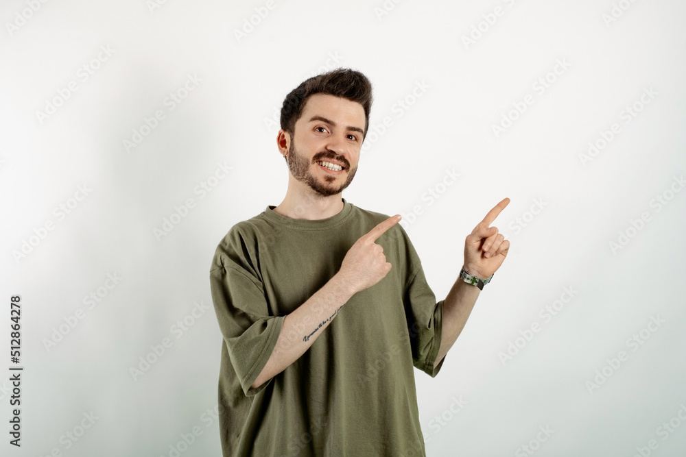Handsome caucasian man wearing khaki t-shirt posing isolated over white background smiling and looking at the camera pointing with two hands and fingers to the side. Handsome caucasian man wearing khaki t-shirt posing isolated over white background smiling and looking at the camera pointing with two hands and fingers to the side.