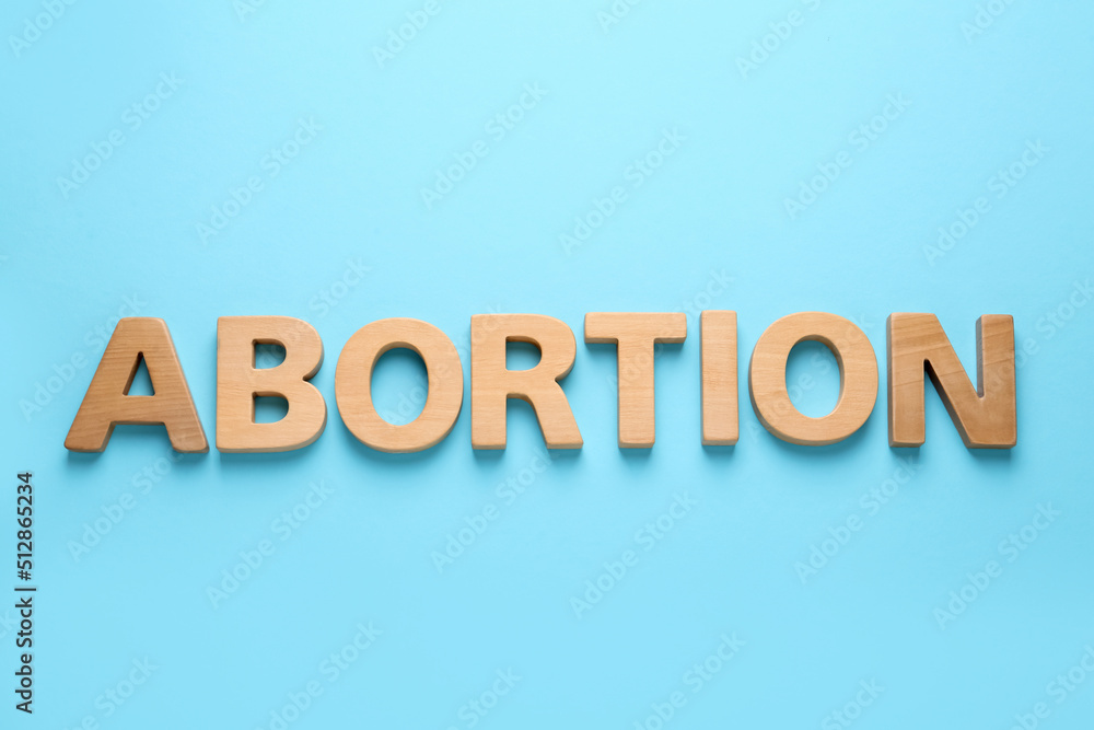 Word Abortion made of wooden letters on light blue background, flat lay Word Abortion made of wooden letters on light blue background, flat lay