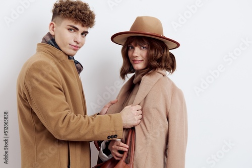 a close horizontal photo of a happy couple in stylish autumn clothes, a woman stands in a hat, and a man holds her by the edges of her coat