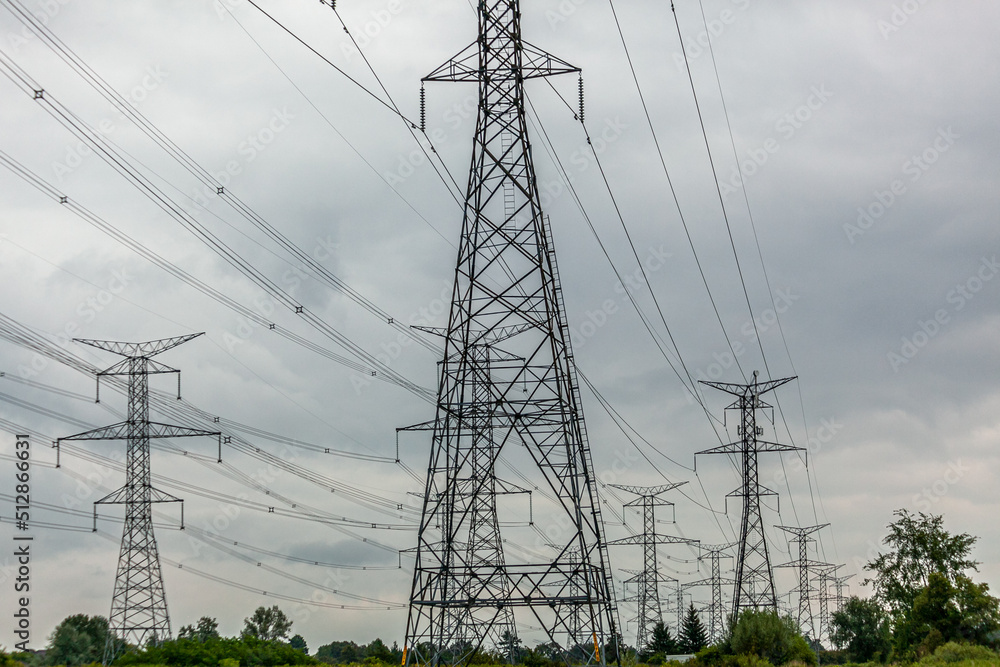 High voltage electricity power lines and transmission towers along a field