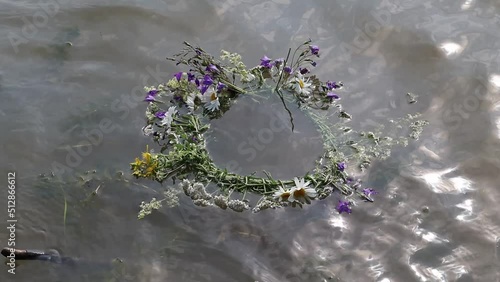 A wreath of summer flowers was thrown into the river and it floats on the water. The concept of the holiday of Ivan Kupala. Girls fuse wreaths of flowers and make wishes. photo