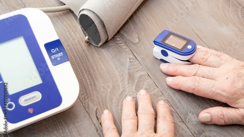 The hands of an elderly person measuring the oxygen level in the blood with a pulse oximeter. Medical monitoring of your health at home: measurement of blood pressure and lung saturation. 