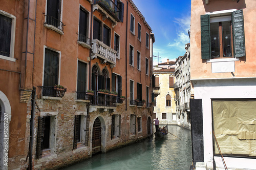 Venice, Italy - September 02, 2018: Wide angle typical view of tourists in gondola in one of the narrow canal with green water, calm romantic concept