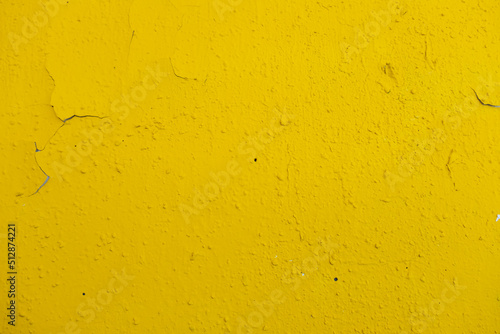old wall painted with yellow paint with cracks and bubbles